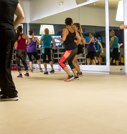 Group of people doing exercises on elliptical machine at gym in workout room flooring
