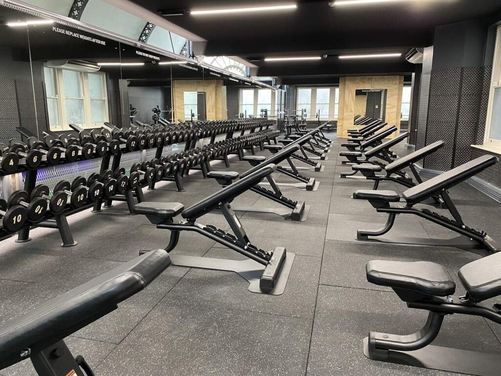 weights area in a gym with black acoustic flooring